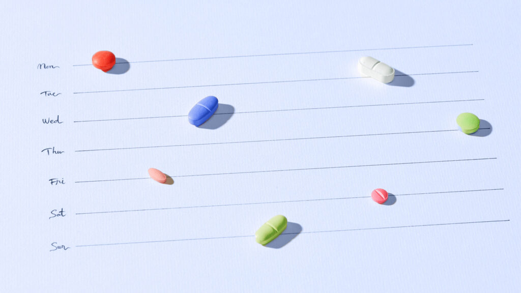 Một số viên thuốc với nhiều màu sắc và hình dạng khác nhau trên một tờ lịch được đánh dấu bằng các ngày trong tuần